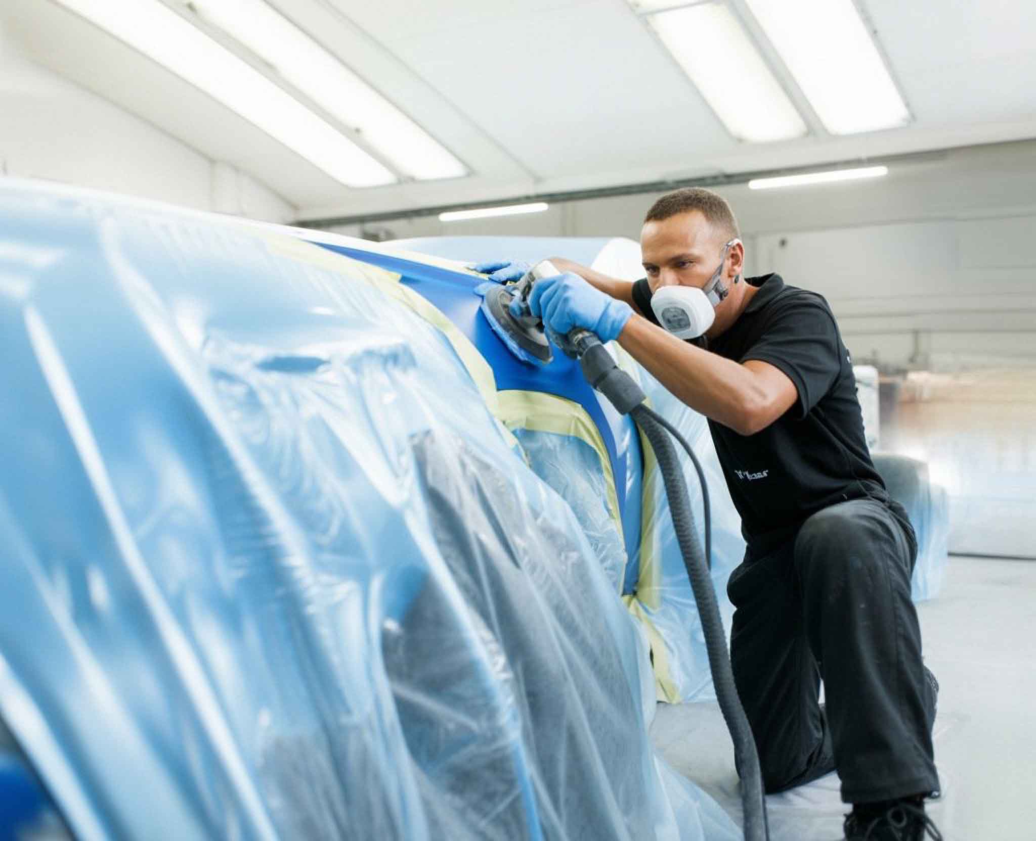 Technician sanding taped vehicle in paint booth - collision repair services - craigs collision